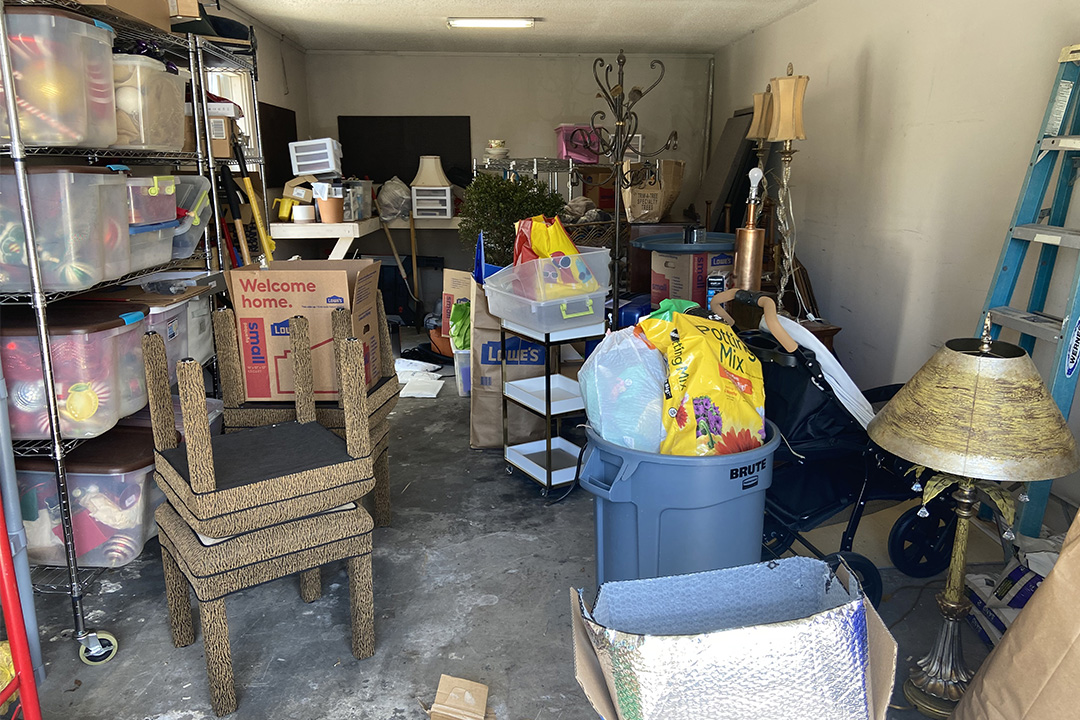 Garage packed full with junk, furniture, and boxes.