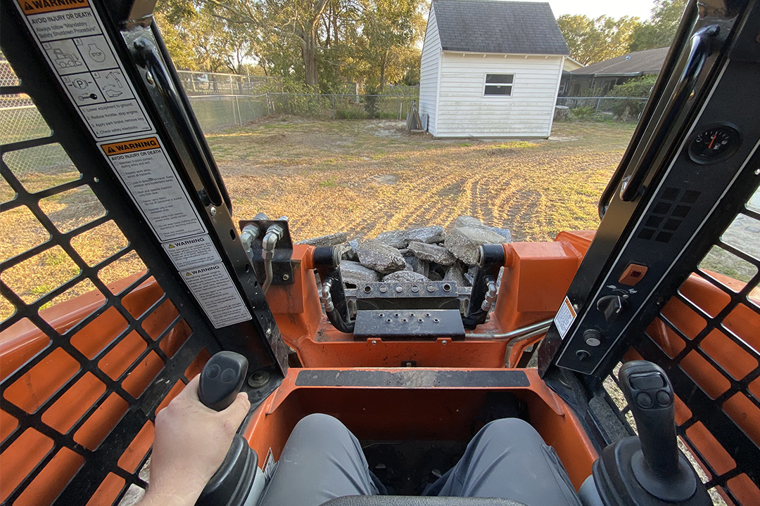 Driving skid steer full of concrete driveway removal debris