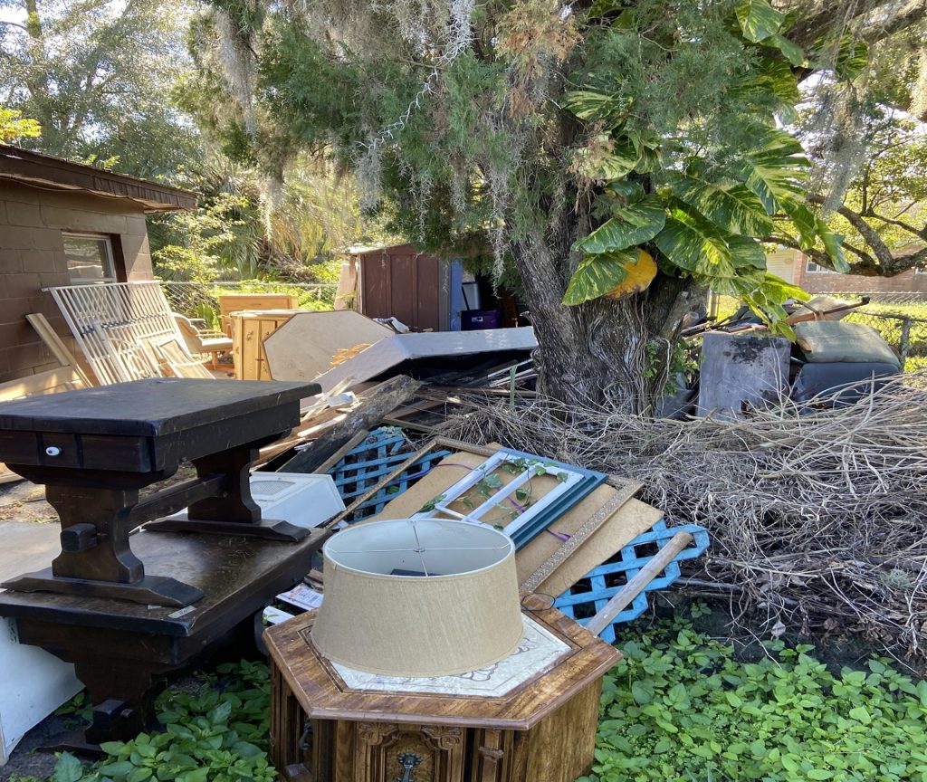 yard filled with trash and furniture hoarder