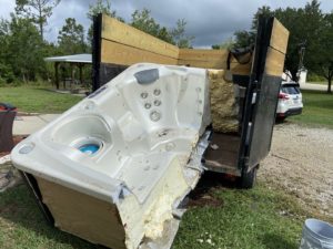 hot tub being loaded into back of junk removal trailer by haul n all junk removal